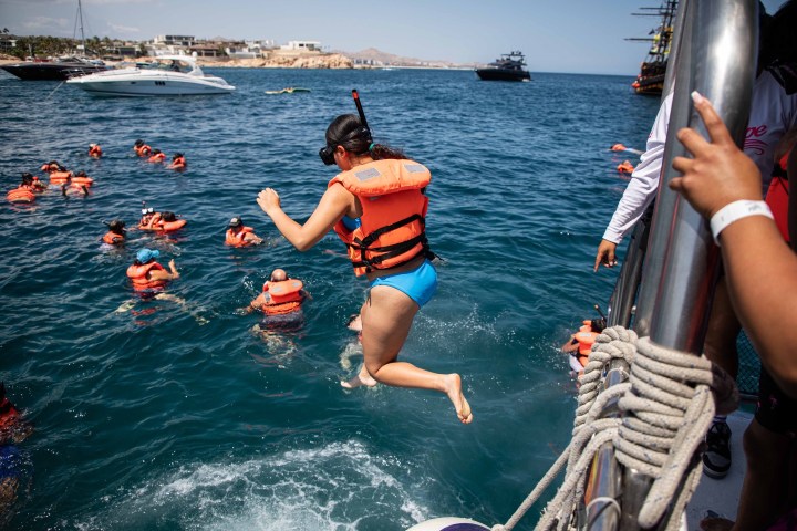 a group of people riding on the back of a boat in the water