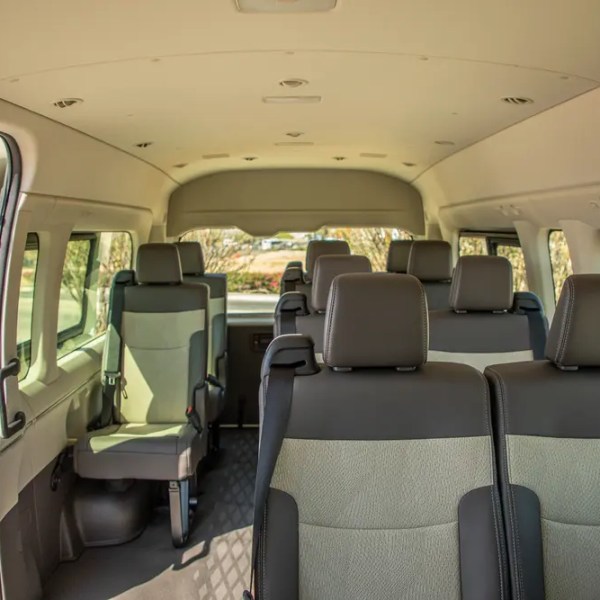 Interior of an empty passenger van with three rows of seats and windows on the sides.